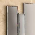 Close-up detail of decorative vertical mirror installation with reflective metallic finish.