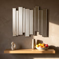 Modern mirrored wall art above a wooden table with decorative vase and fruit bowl.