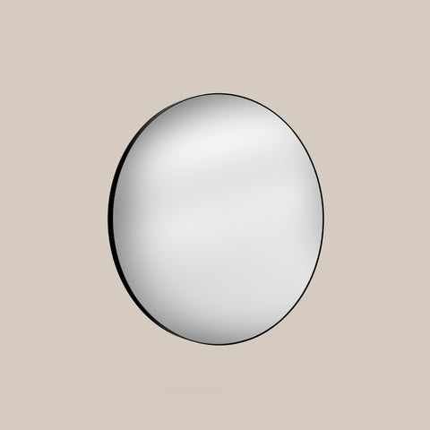 Round mirror with black frame on a beige background