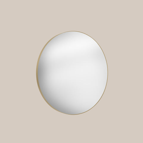 Round mirror with gold frame on a beige background