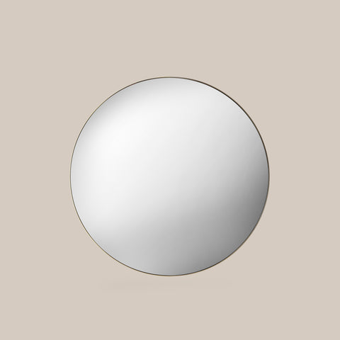 Round Champagne gold mirror on a beige wall