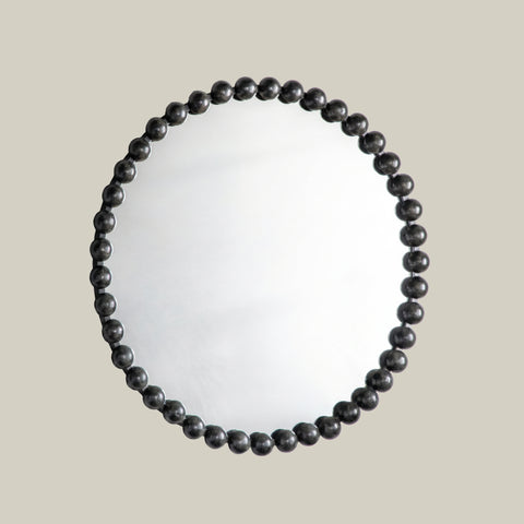 Modern sculptural mirror frame detail with rounded metallic bead embellishments and elegant finish.
