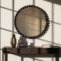Elegant organic-shaped wall mirror with dark metallic sphere detailing styled above a wooden console table.