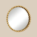 Round wall mirror with a sculptural gold beaded frame and elegant contemporary design against a soft neutral background.