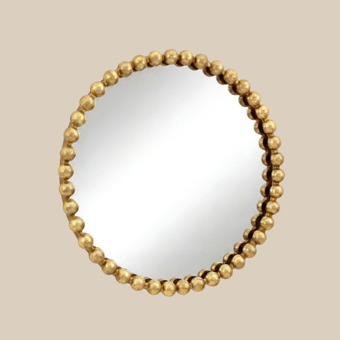 Round wall mirror with a sculptural gold beaded frame and elegant contemporary design against a soft neutral background.