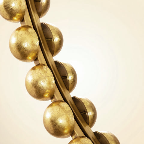 Close-up detail of a decorative mirror frame featuring gold beaded sphere accents with warm metallic texture and sculptural styling.