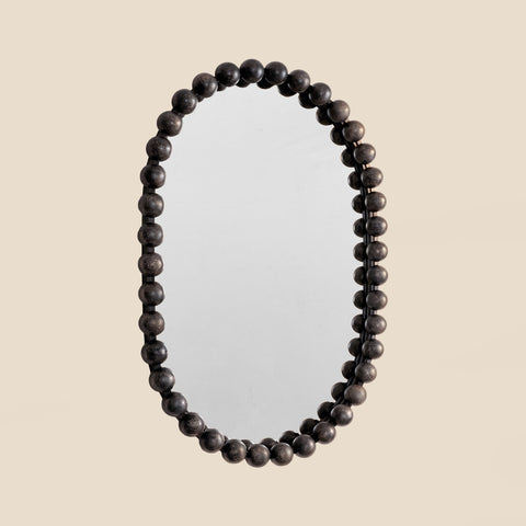 Decorative wall mirror with a sculptural black ball frame and minimalist modern aesthetic.