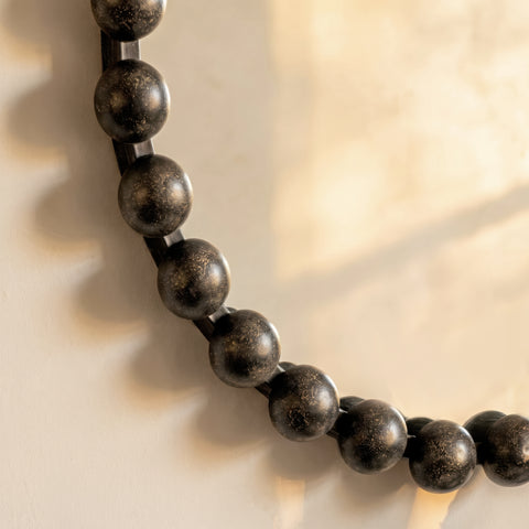Modern sculptural mirror frame detail with rounded metallic bead embellishments and elegant finish.