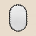 Contemporary statement mirror featuring a rounded silhouette and black beaded frame.