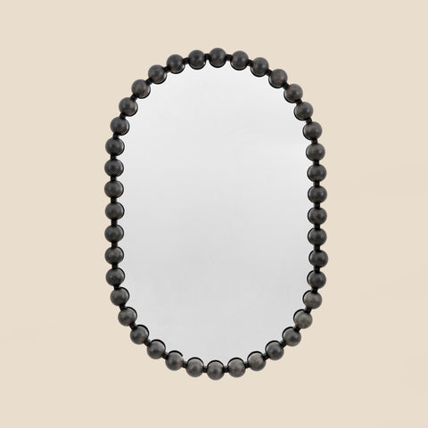 Contemporary statement mirror featuring a rounded silhouette and black beaded frame.