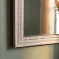 Macro shot of a vintage-inspired grey mirror frame with subtle distressing and decorative edging.