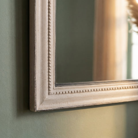 Macro shot of a vintage-inspired grey mirror frame with subtle distressing and decorative edging.