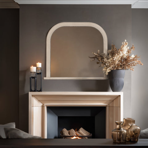 Cream arched wall mirror with subtle beaded detailing styled above a light wood fireplace in a warm, contemporary living room