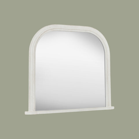 Decorative white mirror frame detail with elegant beading and softly weathered texture