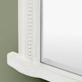 Detailed view of a textured white mirror frame with decorative beaded trim and soft distressed accents.