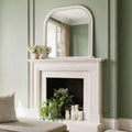 Traditional arched mirror with subtle beaded detailing reflecting a bright, neutral interior.