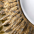 Decorative mirror frame detail featuring layered sunburst spokes, textured gold finish and subtle distressed detailing.