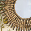 Detailed close-up of a decorative gold sunburst mirror showcasing textured rays, distressed metallic finish and vintage-inspired character.