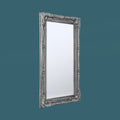 Decorative standing floor mirror with ornate silver frame and classic carved accents.