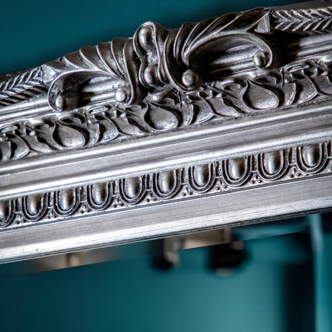 Close-up of decorative baroque-inspired mirror frame featuring intricate silver detailing.