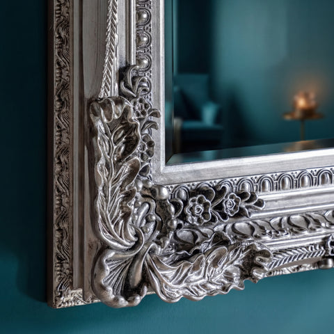 Elegant antique silver mirror frame detail with textured carved embellishments and classic styling.