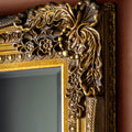 Elegant antique gold mirror frame detail with sculpted floral and scroll motifs.