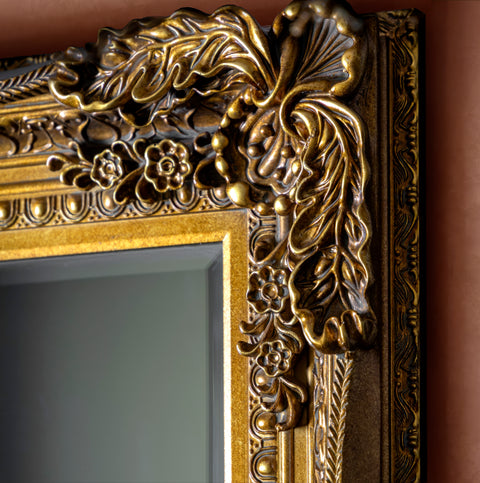 Elegant antique gold mirror frame detail with sculpted floral and scroll motifs.
