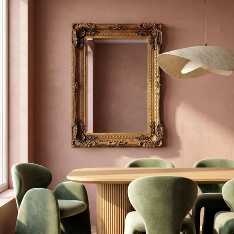 Ornate rectangular wall mirror with an antique gold carved frame displayed above a wooden dining table in a warm contemporary interior.