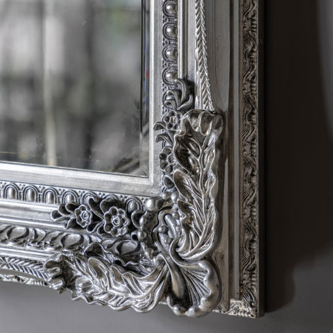 Detailed view of a vintage-style silver mirror frame with embossed ornamental carvings.