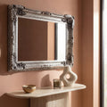 Elegant vintage-style wall mirror with intricate silver detailing in a warm modern interior.
