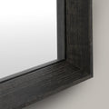 Close-up of a black wood-framed mirror on a light grey background