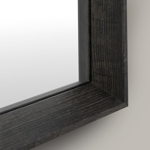 Close-up of a black wood-framed mirror on a light grey background