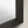 Close-up of a mirror with a dark wooden frame on a light background