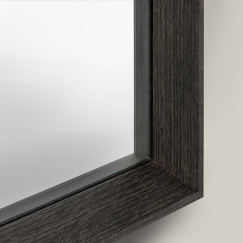 Close-up of a mirror with a dark wooden frame on a light background