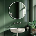 Round wall mirror with a slim white frame above a modern white basin sink in a dark green contemporary bathroom.