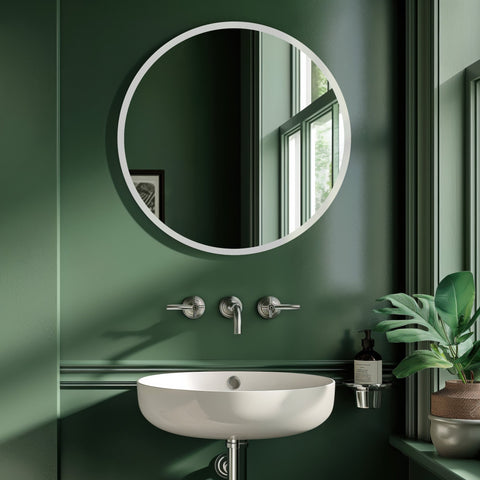 Round wall mirror with a slim white frame above a modern white basin sink in a dark green contemporary bathroom.
