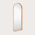 leaner mirror with a oak frame at an angle on a light grey background