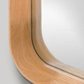 Wooden frame of a rounded edge oak mirror on a light grey background