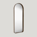 Large arched walnut leaner mirror on a soft grey background