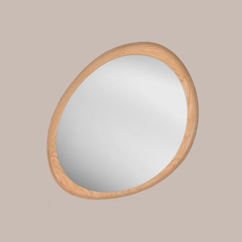Round organic shaped mirror with a oak wooden frame on a beige background