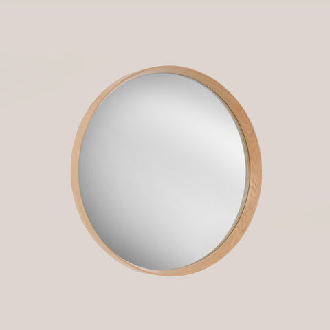 Round oak framed mirror on a beige background