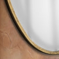 Detailed close-up of a gold organic mirror showcasing softly aged metallic texture, fluid curves and warm antique-inspired detailing.
