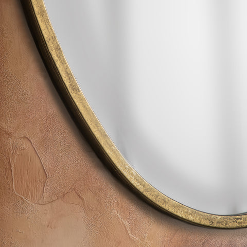 Detailed close-up of a gold organic mirror showcasing softly aged metallic texture, fluid curves and warm antique-inspired detailing.