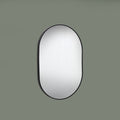 Round mirror with black frame on a green background
