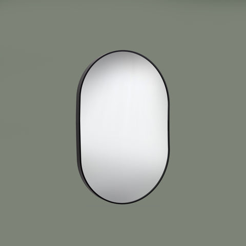 Round mirror with black frame on a green background