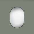 Round mirror with black frame on a green background face on