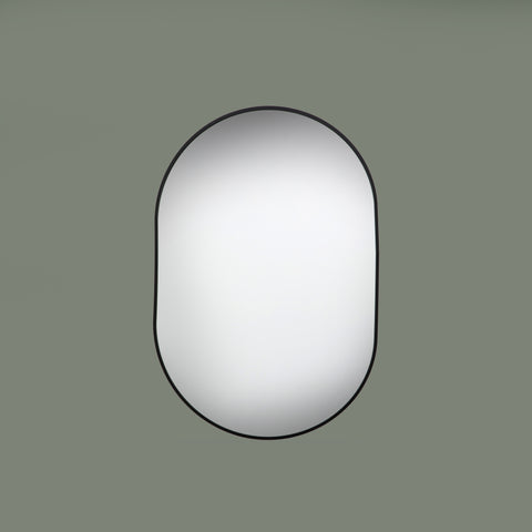 Round mirror with black frame on a green background face on