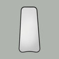 Modern full-length mirror featuring softened curves, a slim dark frame and a distinctive contemporary silhouette.
