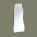 Rectangular organic shaped leaner mirror with gold effect frame on a light green background
