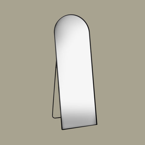 Black arch cheval mirror at an angle with a beige background